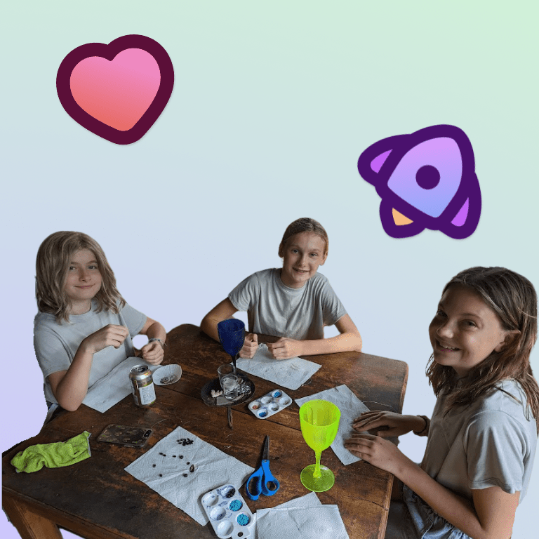 three kids smiling around a table doing crafts and hands-on activities
