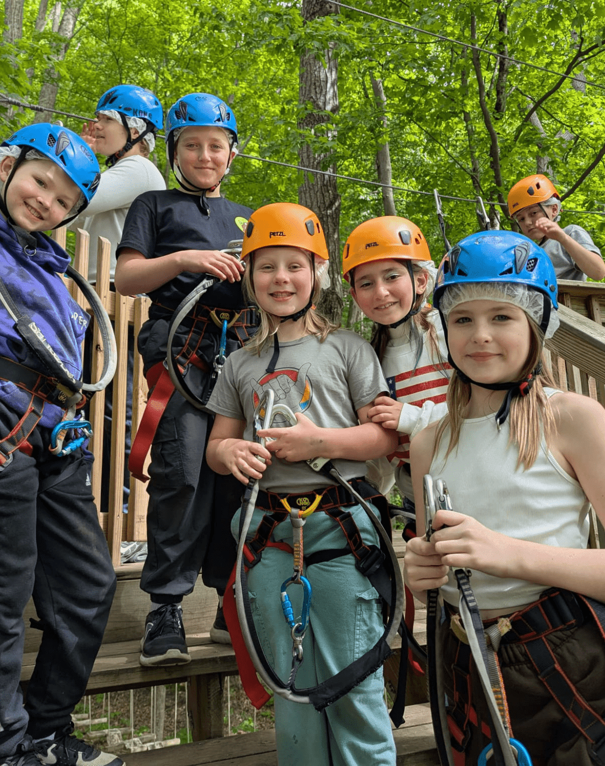 group of Prisma students wearing helmets and harnesses at an outdoor zip line adventure course