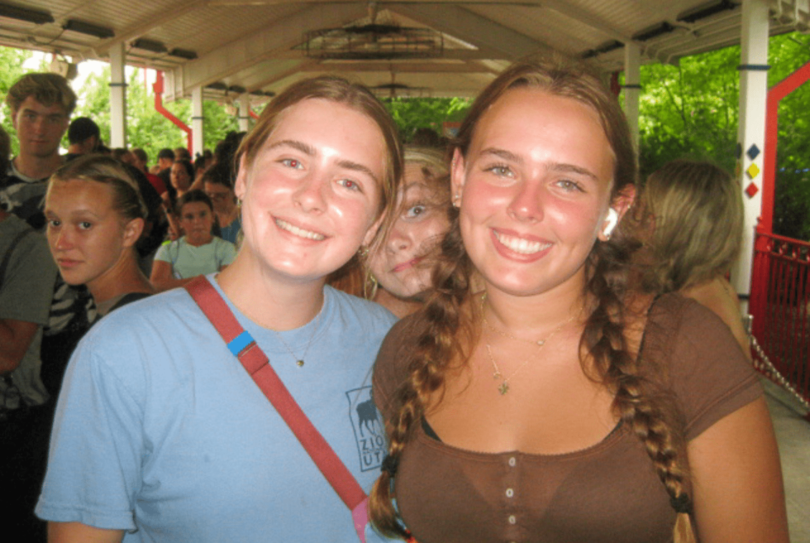 two Prisma learners smiling together at an outdoor venue with green trees behind them