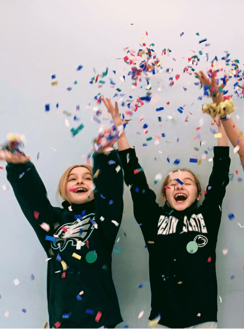 two Prisma homeschool students throwing colorful confetti in the air and laughing