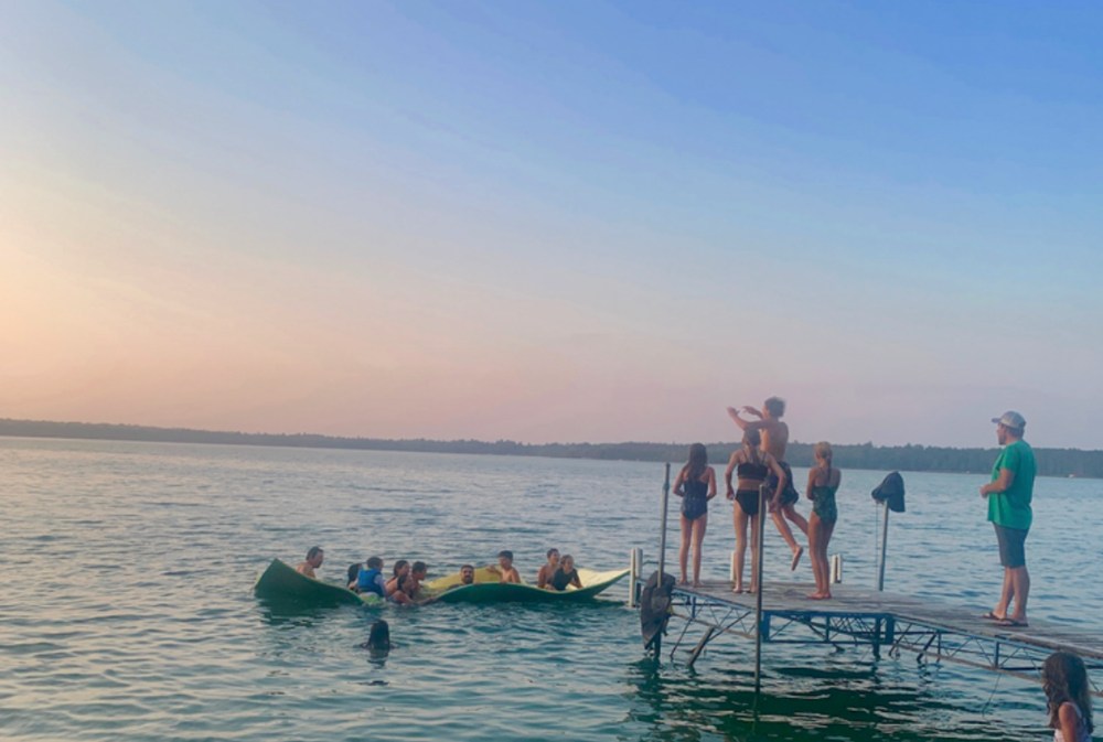 Prisma students swimming and standing on a lake dock at sunset during retreat
