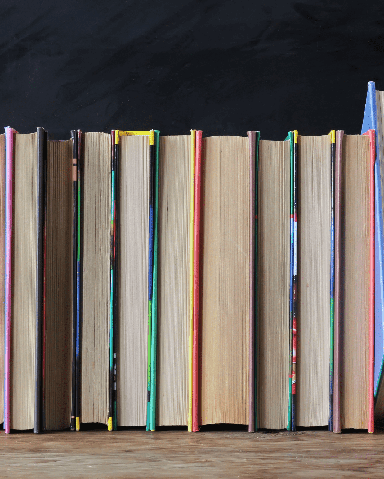 row of colorful books standing upright against a dark background