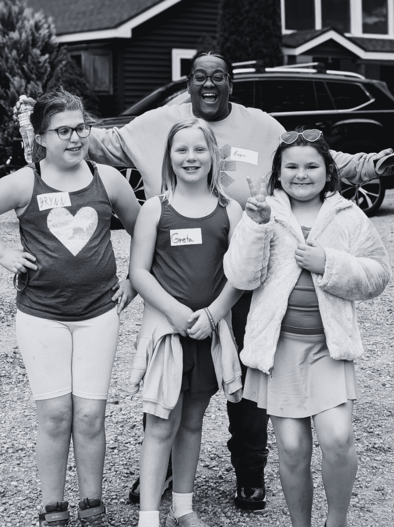 three Prisma lower school girls smiling with their coach at an in-person meetup