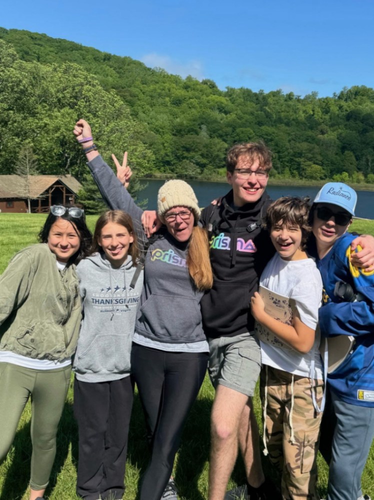 group of six Prisma students posing outdoors by a lake at a community meetup
