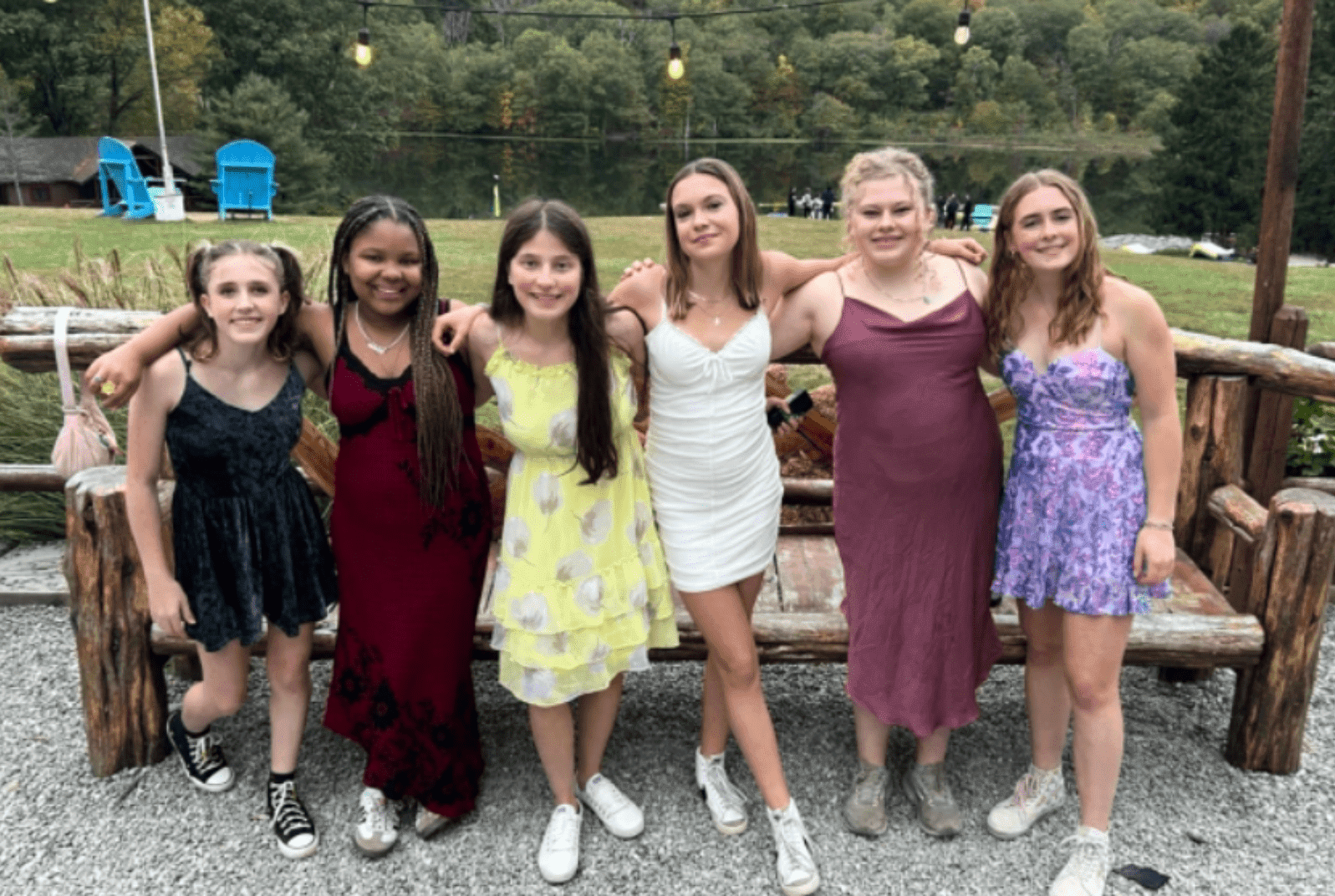 six Prisma learners in dresses posing together at an outdoor evening event