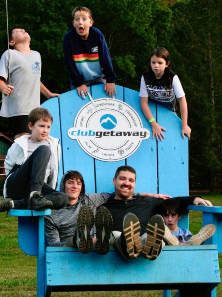 Prisma kids and coaches posing on an oversized blue chair at Club Getaway