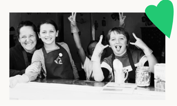 parent and two kids laughing together in aprons during a cooking activity