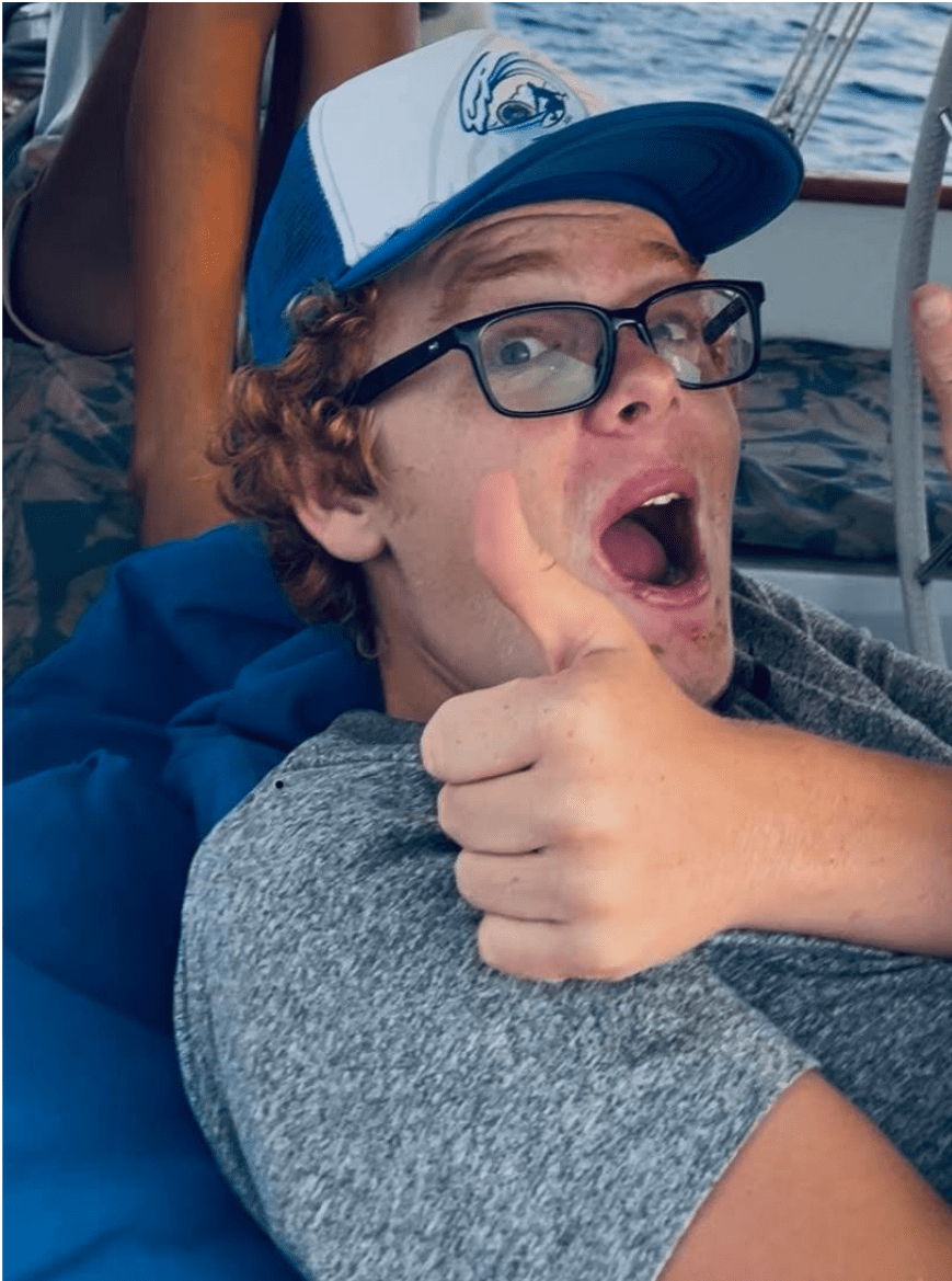 Prisma high school student giving thumbs up on a sailboat at sea