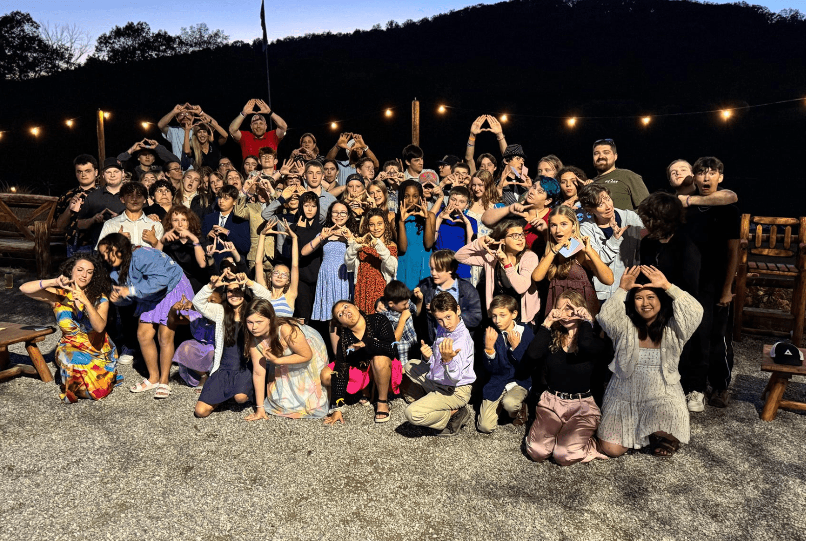 large group of Prisma students making heart shapes with their hands at an outdoor evening event