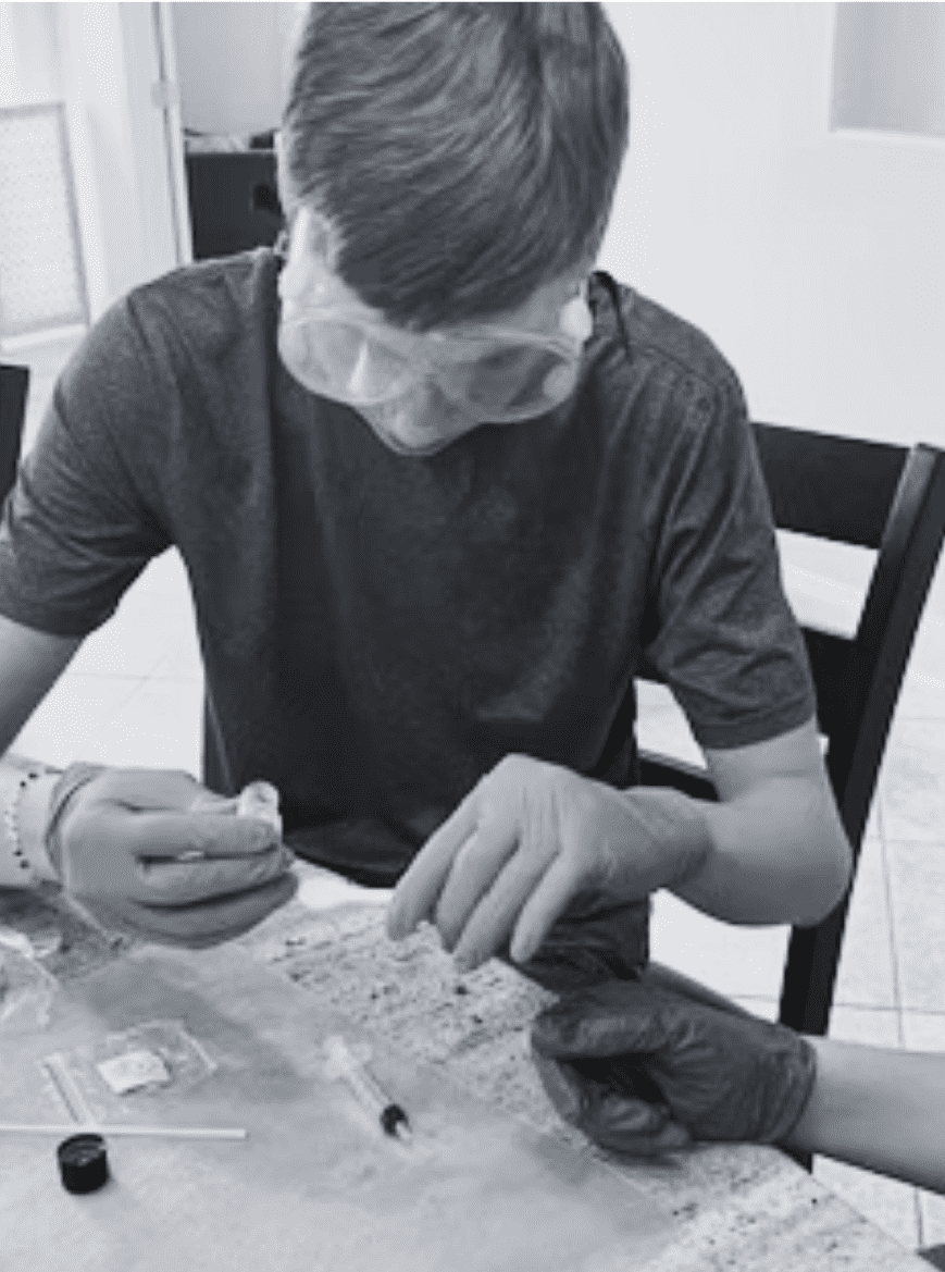 Prisma student wearing safety goggles and gloves performing a hands-on science experiment
