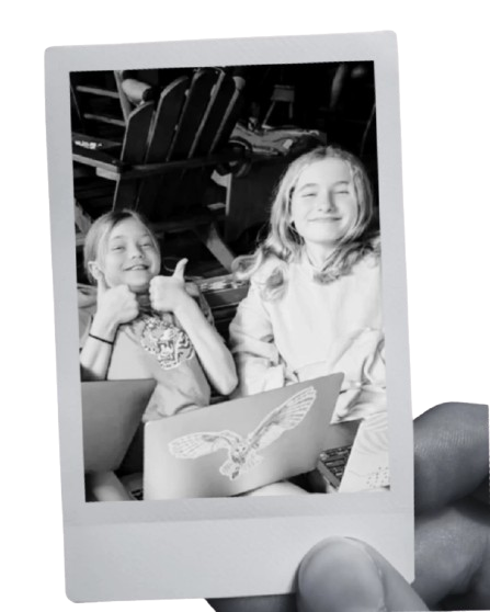 polaroid-style photo of two smiling Prisma middle school students holding artwork together